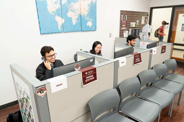 Students answering phones at a row of phone banks in the International Student & Scholar Services office.