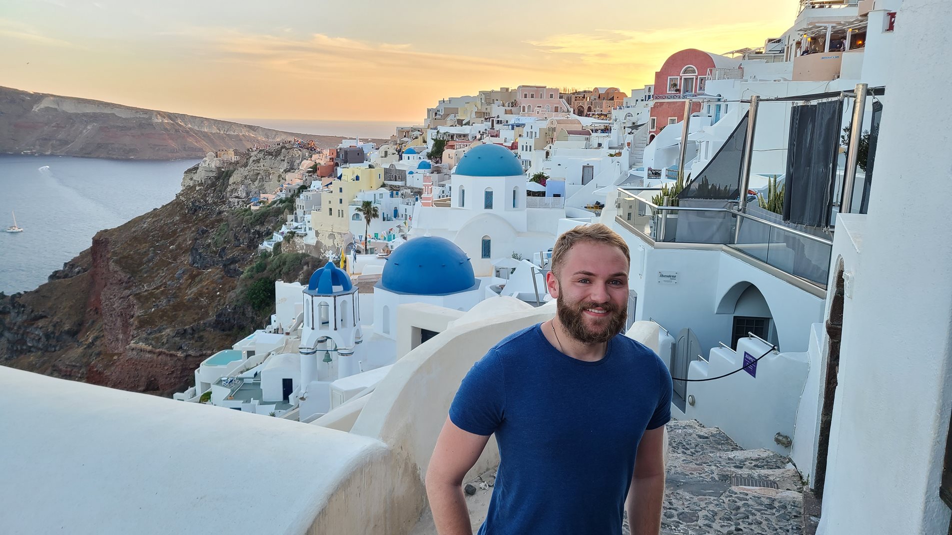 Man standing in front of a view of domed building in Santorini, Greece
