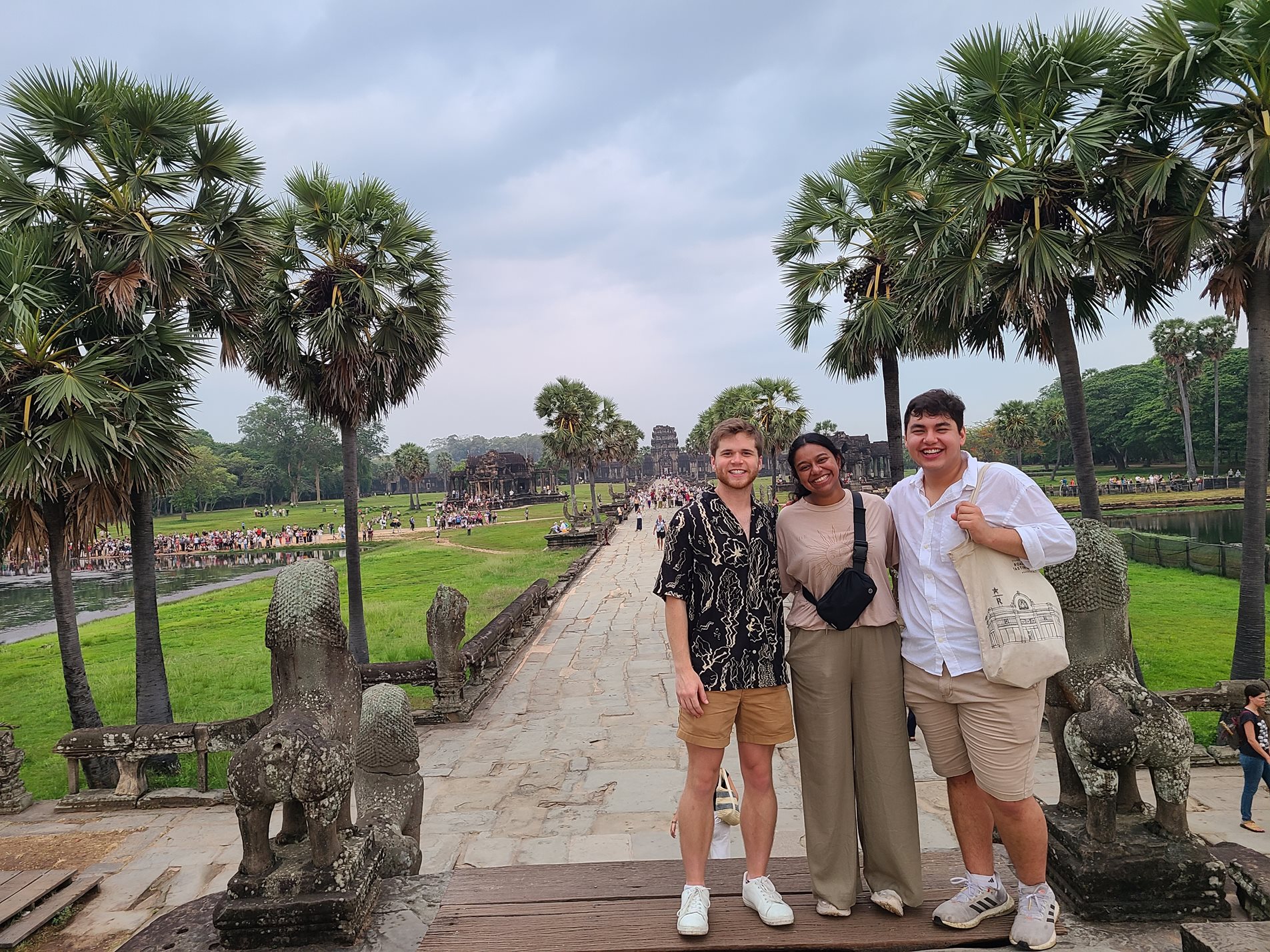 Three people standing in front of Ankor Wat complex in Cambodia