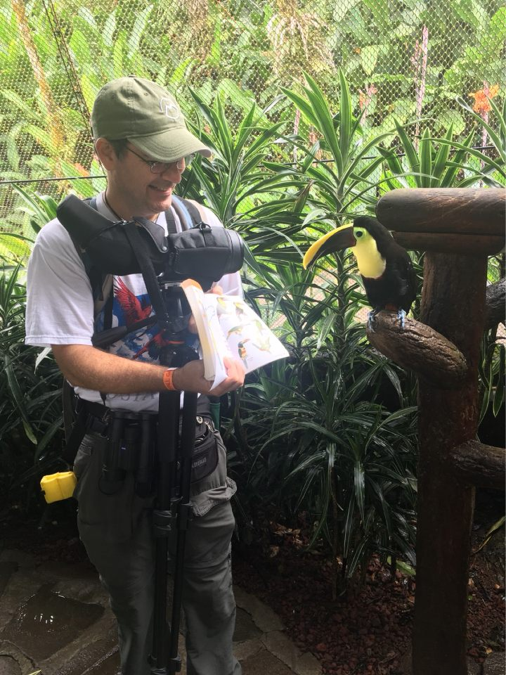 Dr. Donald Brightsmith in Costa Rica showing a toucan a book about toucans.