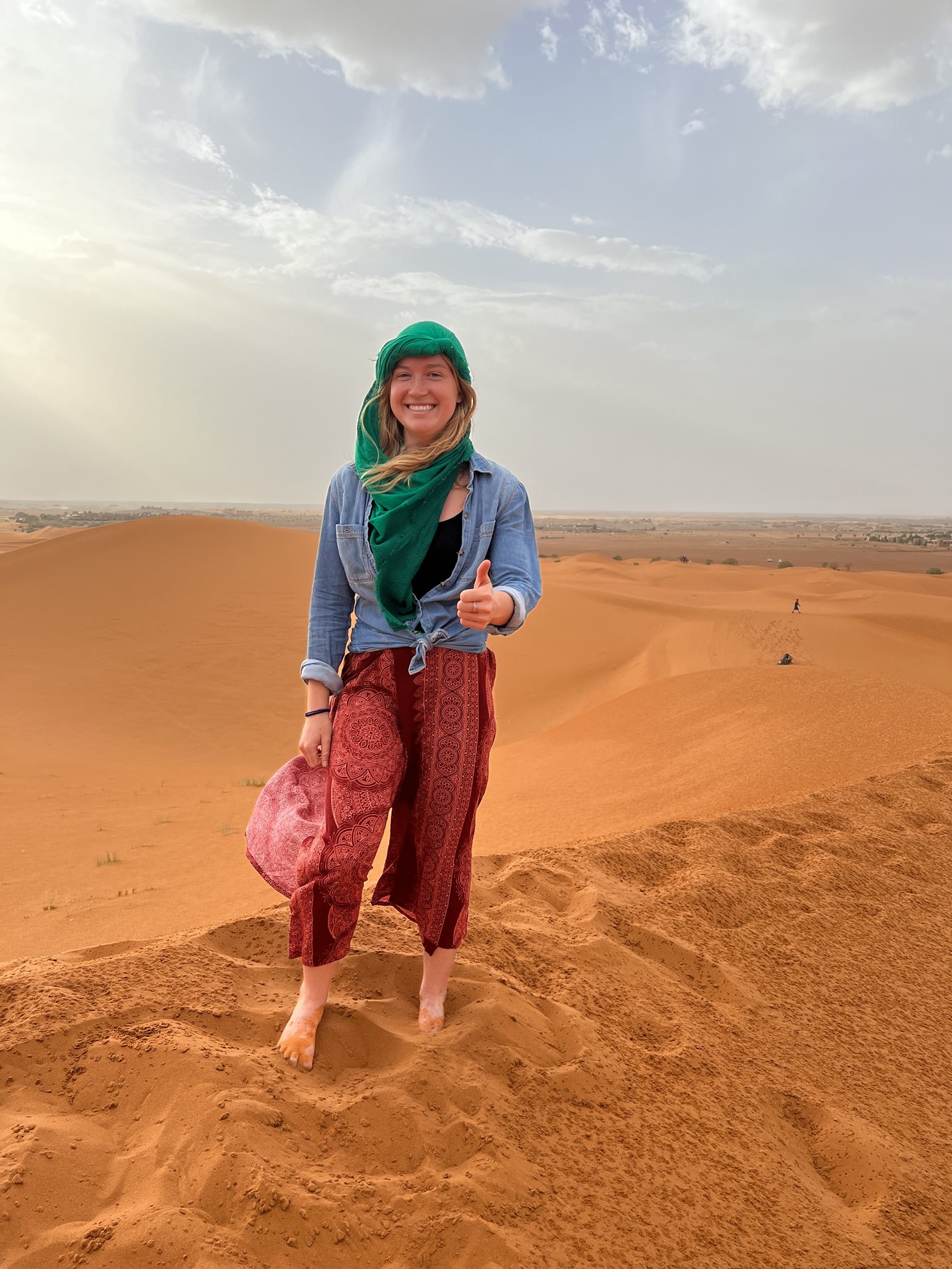 Woman giving thumbs up on sand dunes in Africa