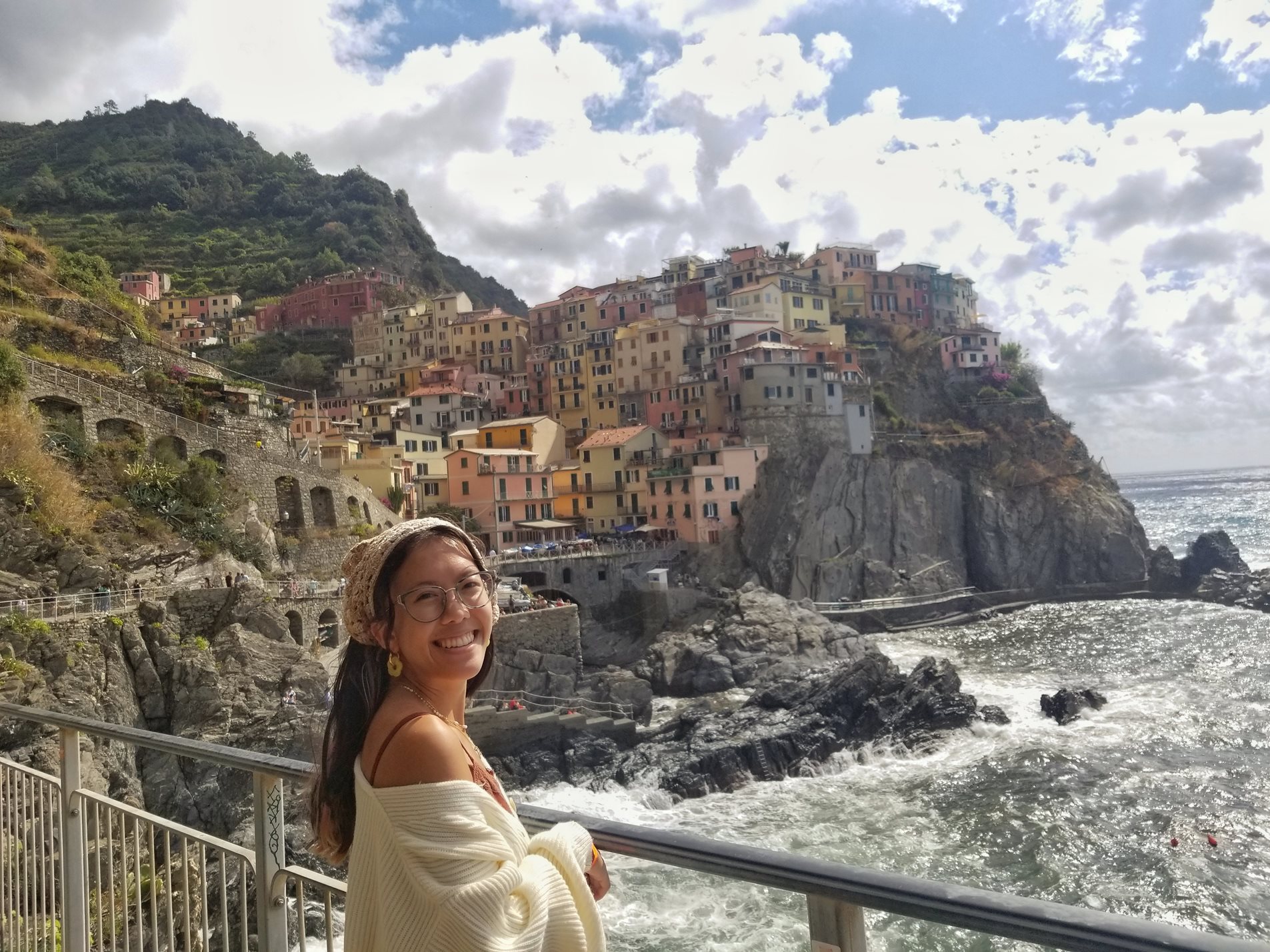 Woman standing in front of a view of buildings on the slopes of Manarolae, Italy